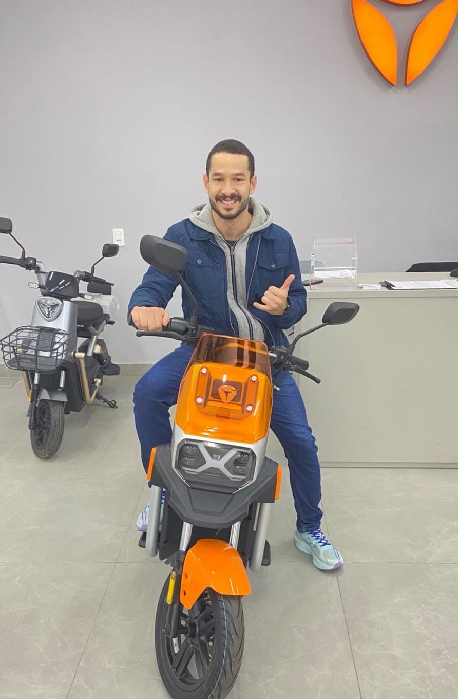 Cliente Yadea com a sua moto elétrica na loja