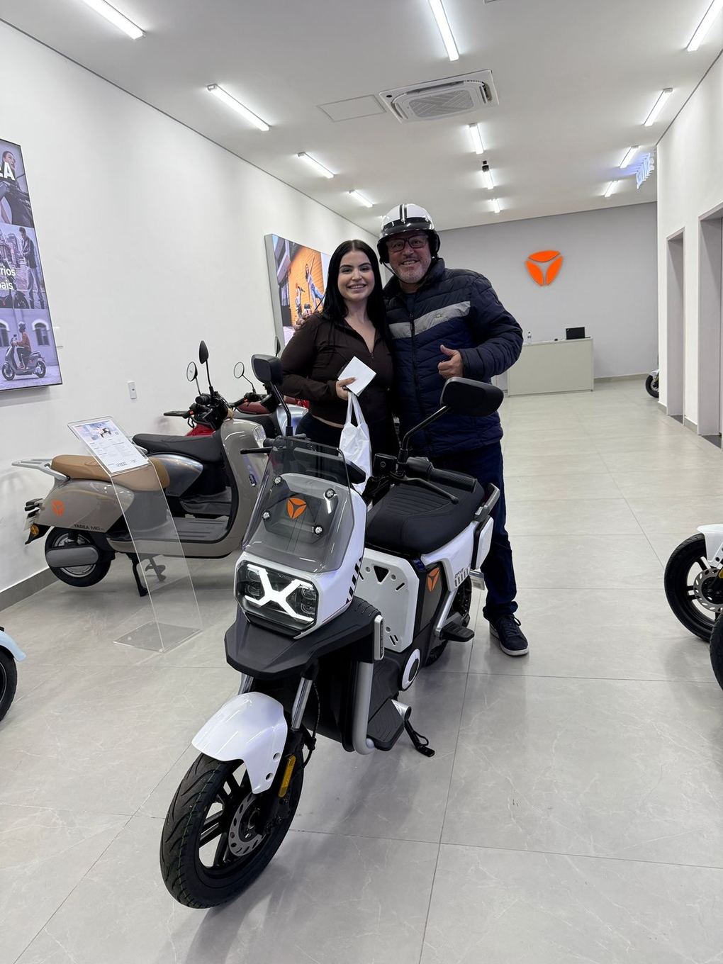 Cliente Yadea com a sua moto elétrica na loja